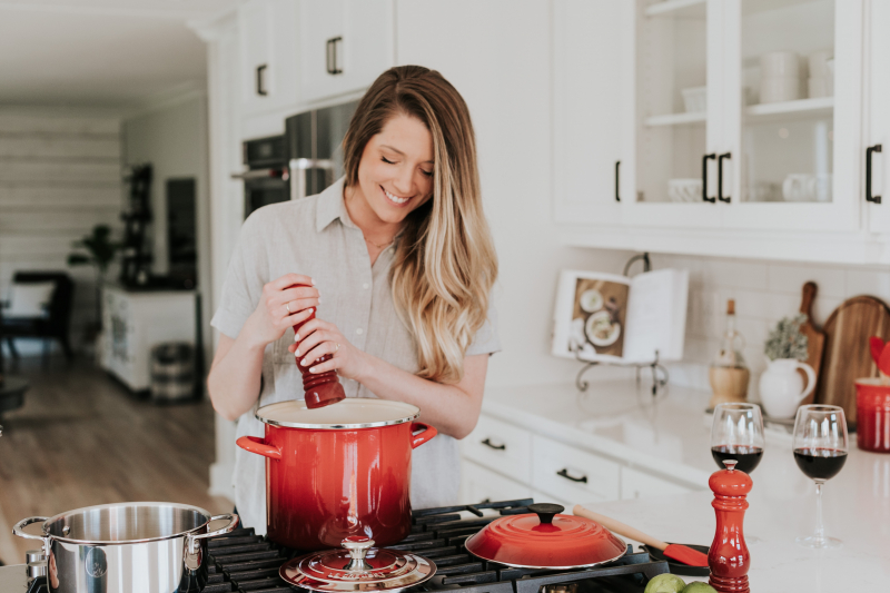 Photo by Becca Tapert on Unsplash: https://unsplash.com/photos/smiling-woman-standing-and-putting-pepper-on-stock-pot-RjmGzTg4_mw