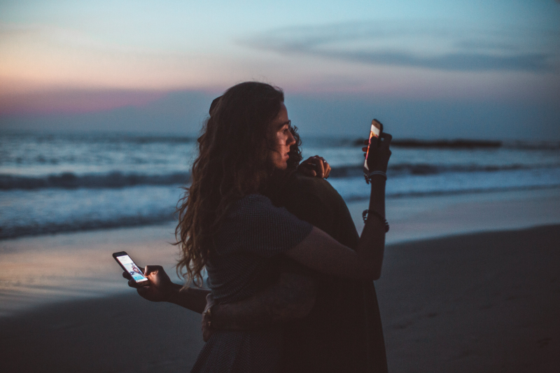 Photo by ROMAN ODINTSOV: https://www.pexels.com/photo/couple-hugging-and-using-smartphone-near-sea-on-sunset-4555321/