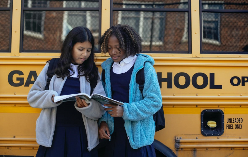 Photo on Pexels: https://www.pexels.com/photo/multiracial-schoolgirls-with-workbook-near-bus-in-city-5896482/